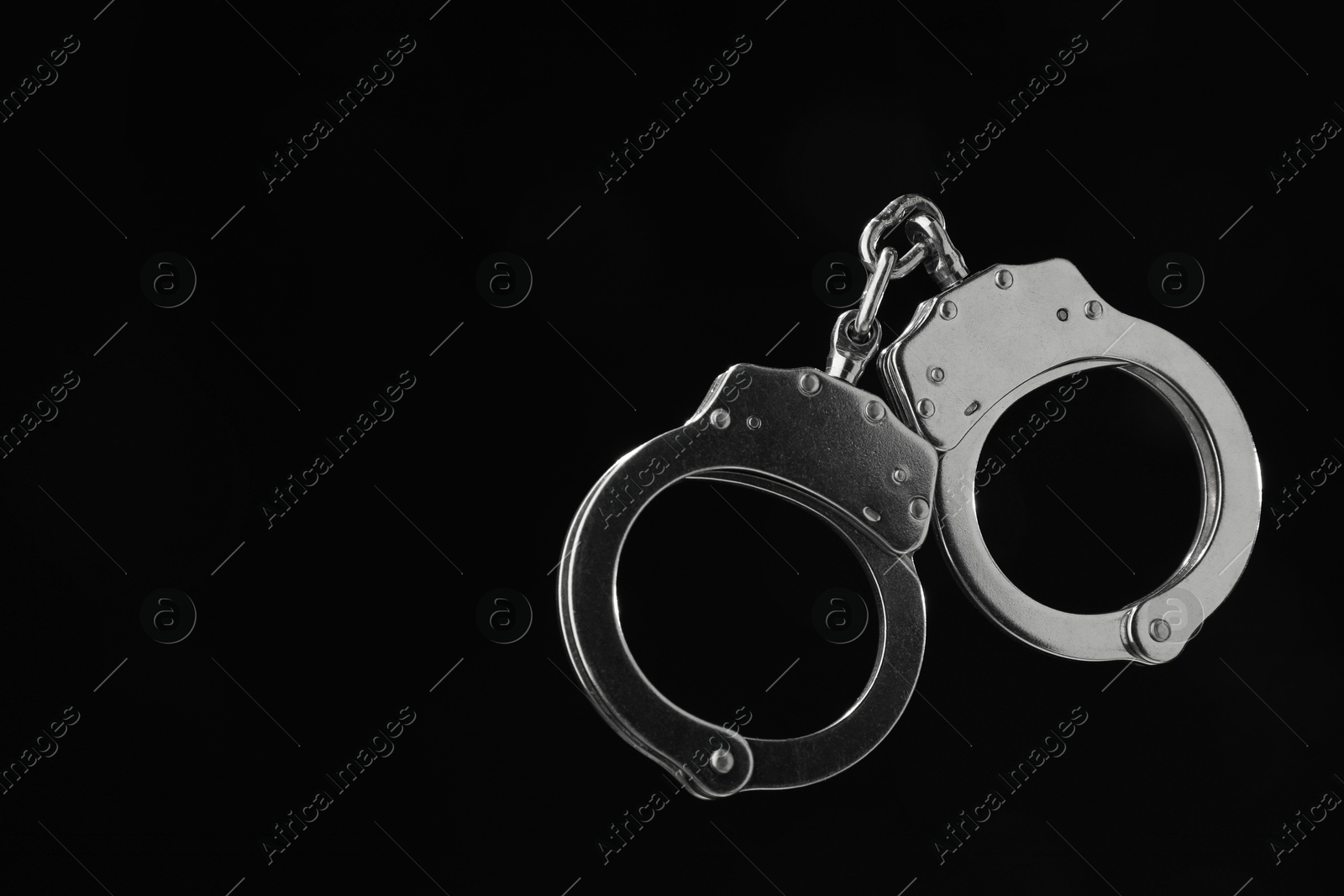 Photo of Metal chain handcuffs on black background, closeup. Space for text