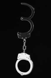 Photo of Metal chain handcuffs on black background, closeup