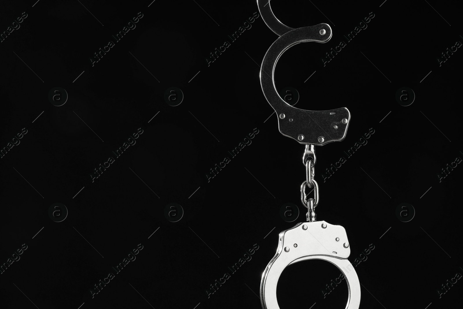 Photo of Metal chain handcuffs on black background, closeup. Space for text