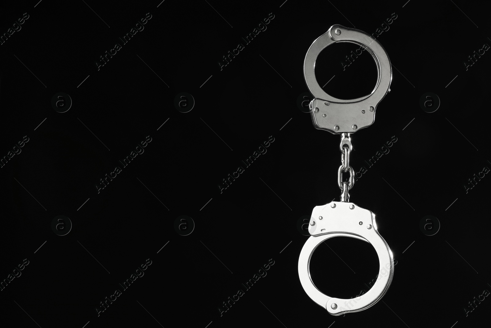 Photo of Metal chain handcuffs on black background, closeup. Space for text