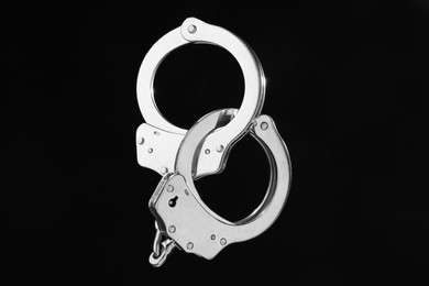 Photo of Metal chain handcuffs on black background, closeup