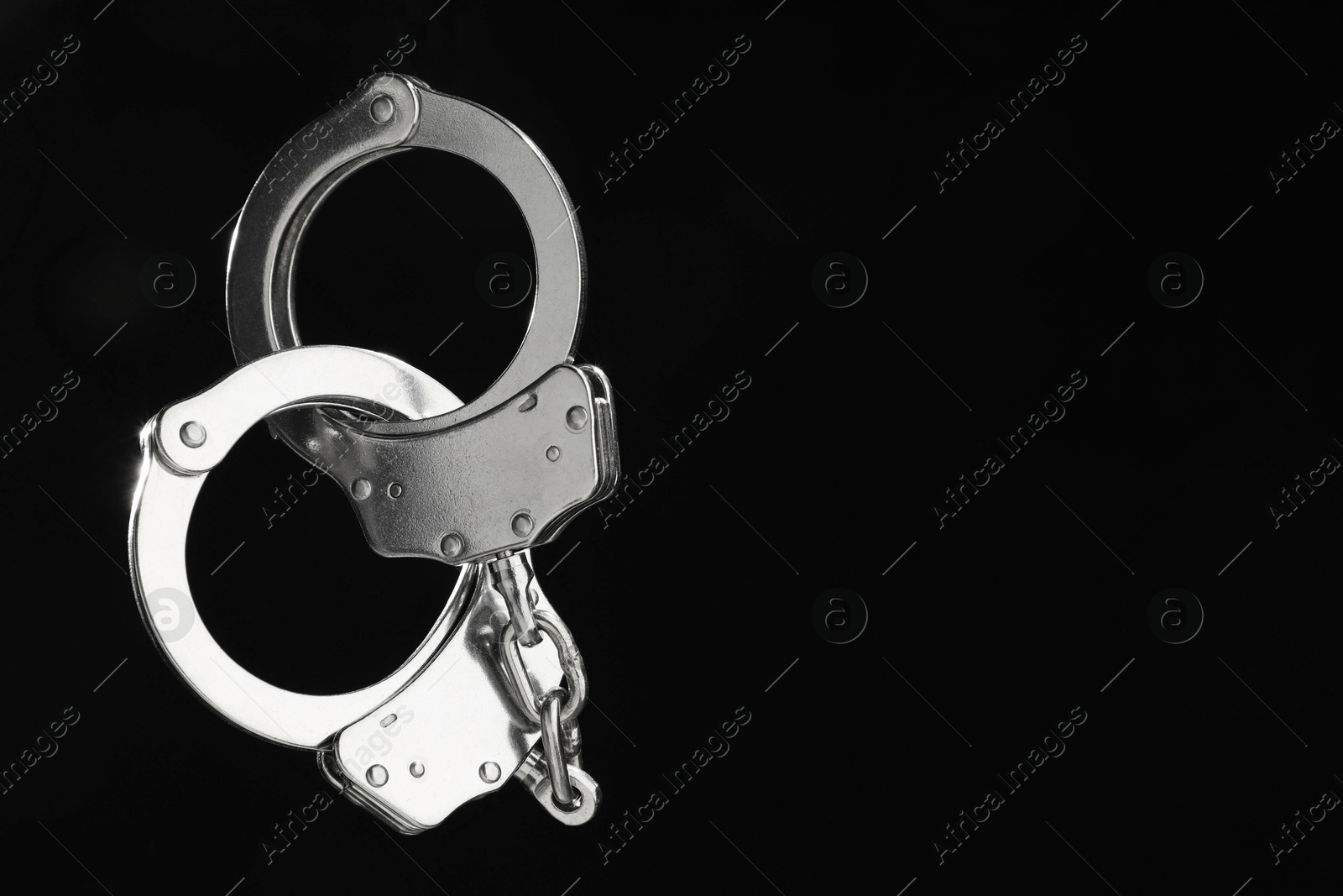 Photo of Metal chain handcuffs on black background, closeup. Space for text