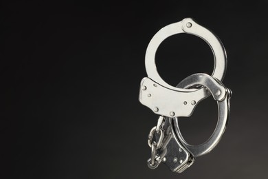 Photo of Metal chain handcuffs on black background, closeup. Space for text