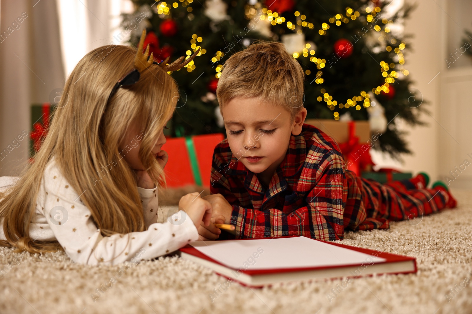 Photo of Little kids writing letter to Santa Claus on floor at home. Christmas celebration