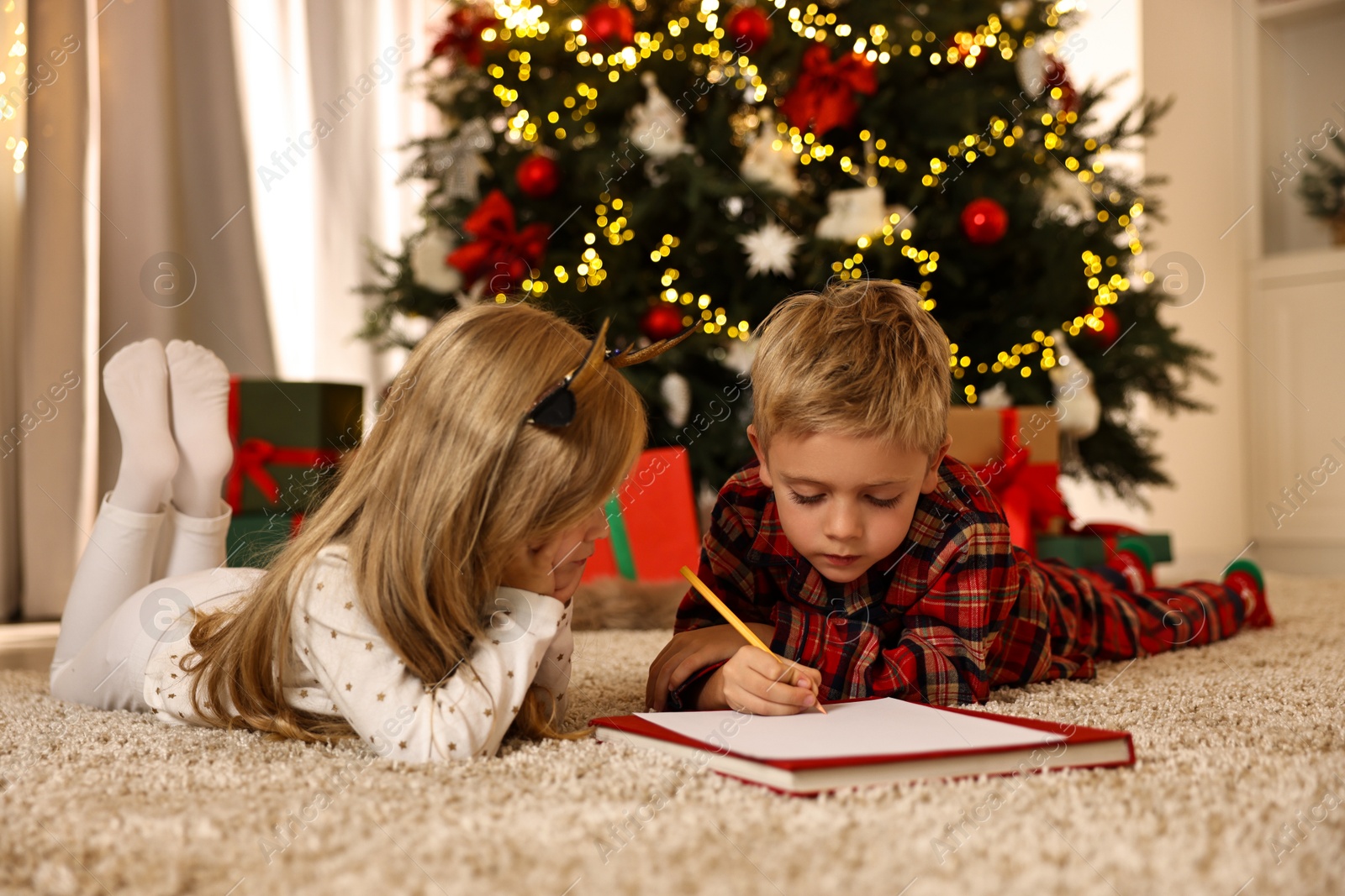 Photo of Little kids writing letter to Santa Claus on floor at home. Christmas celebration