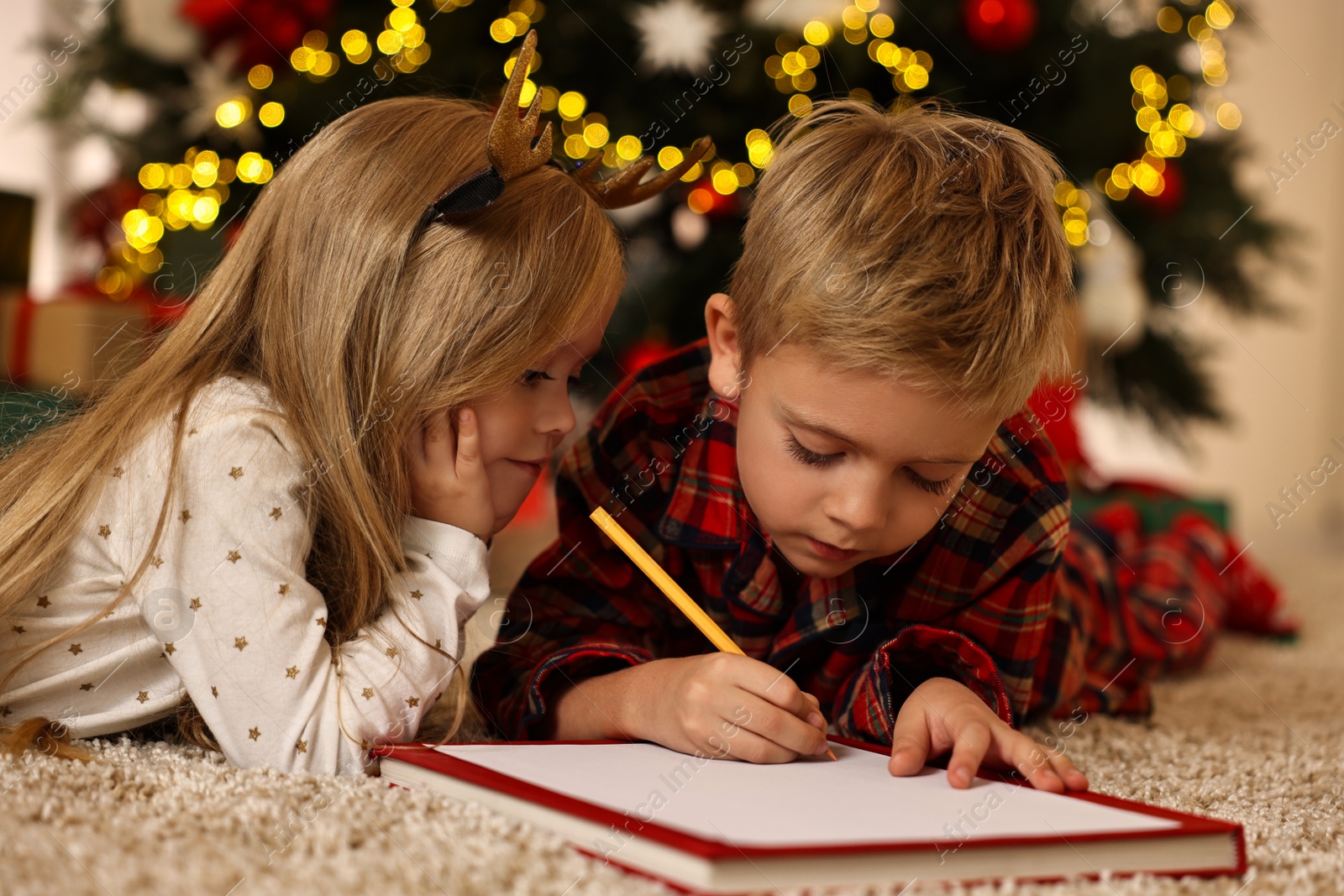 Photo of Little kids writing letter to Santa Claus on floor at home. Christmas celebration