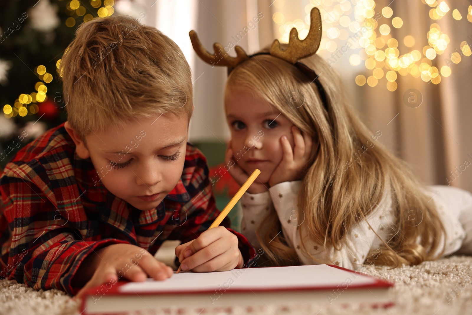 Photo of Little kids writing letter to Santa Claus on floor at home. Christmas celebration