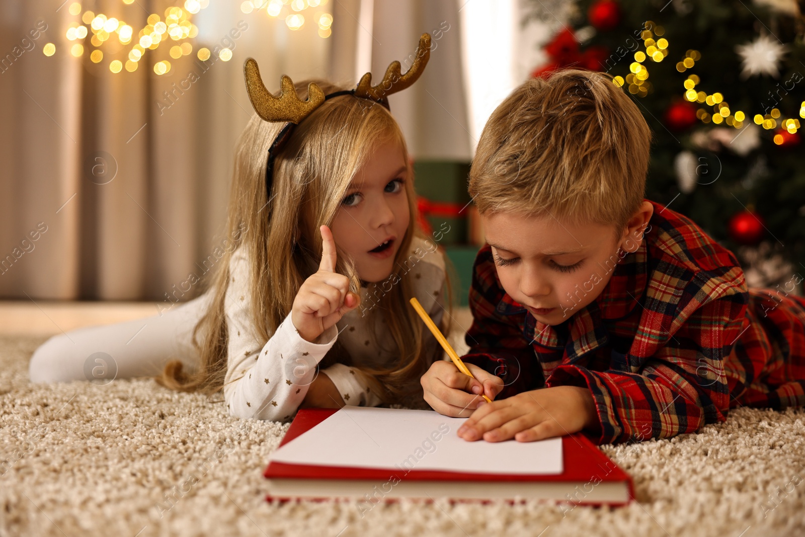 Photo of Little kids writing letter to Santa Claus on floor at home. Christmas celebration