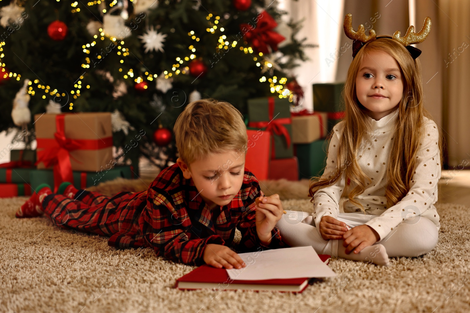 Photo of Little kids writing letter to Santa Claus on floor at home. Christmas celebration