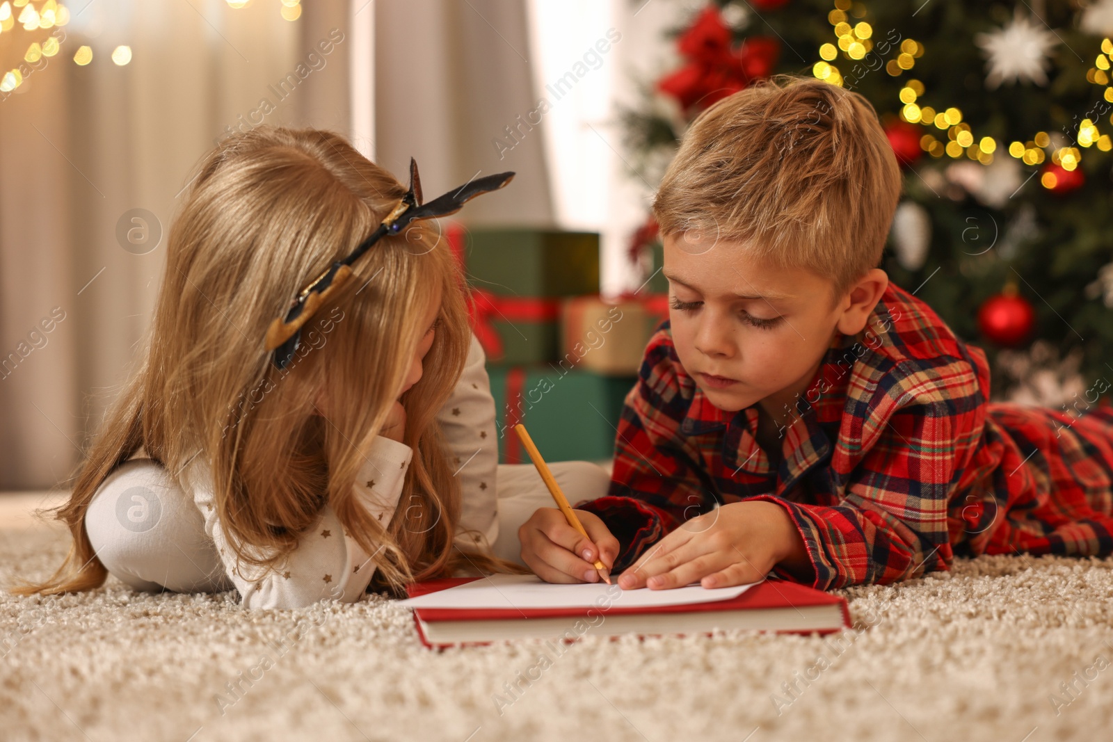 Photo of Little kids writing letter to Santa Claus on floor at home. Christmas celebration