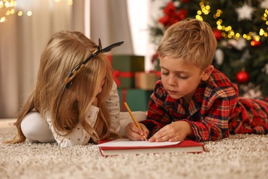 Little kids writing letter to Santa Claus on floor at home. Christmas celebration