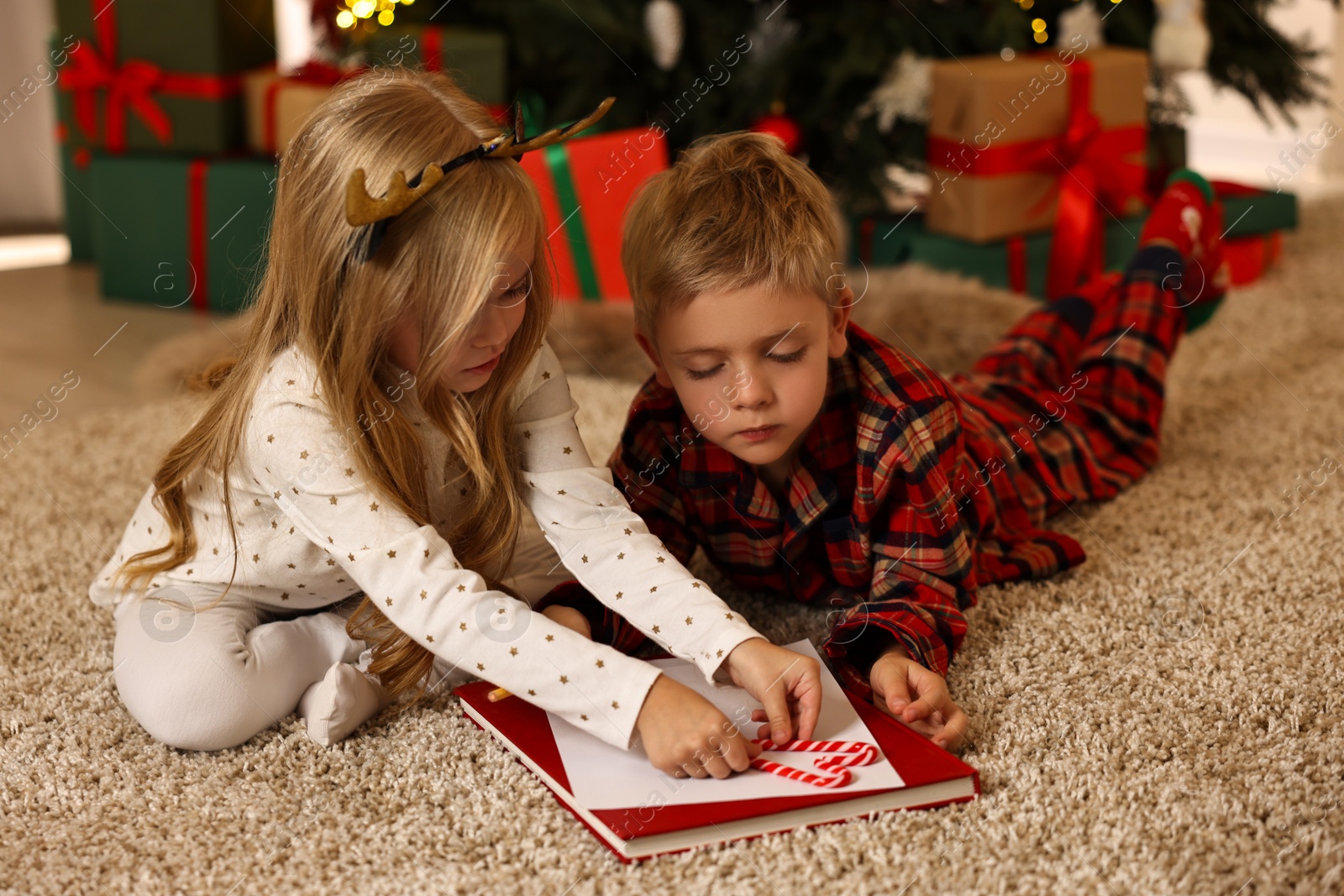 Photo of Little kids writing letter to Santa Claus on floor at home. Christmas celebration