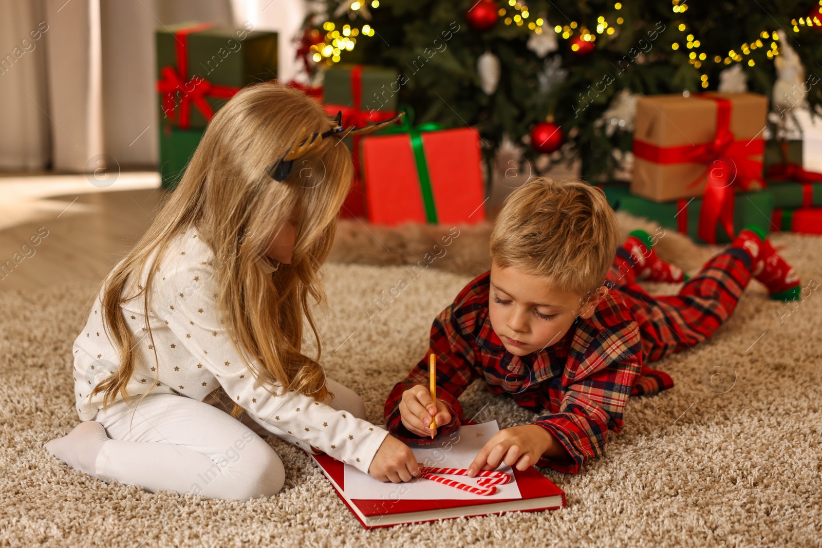 Photo of Little kids writing letter to Santa Claus on floor at home. Christmas celebration