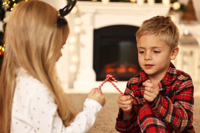 Photo of Little kids with candy canes on floor at home. Christmas celebration