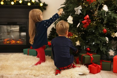 Photo of Little kids decorating Christmas tree at home