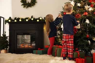 Photo of Little kids decorating Christmas tree at home