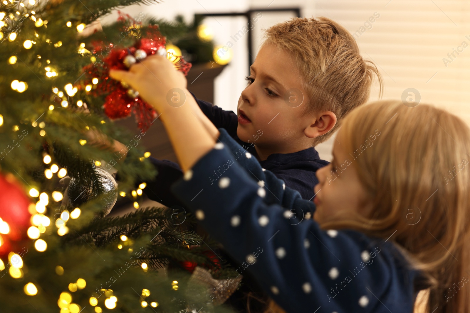 Photo of Little kids decorating Christmas tree at home