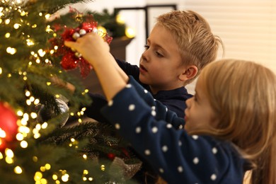 Photo of Little kids decorating Christmas tree at home