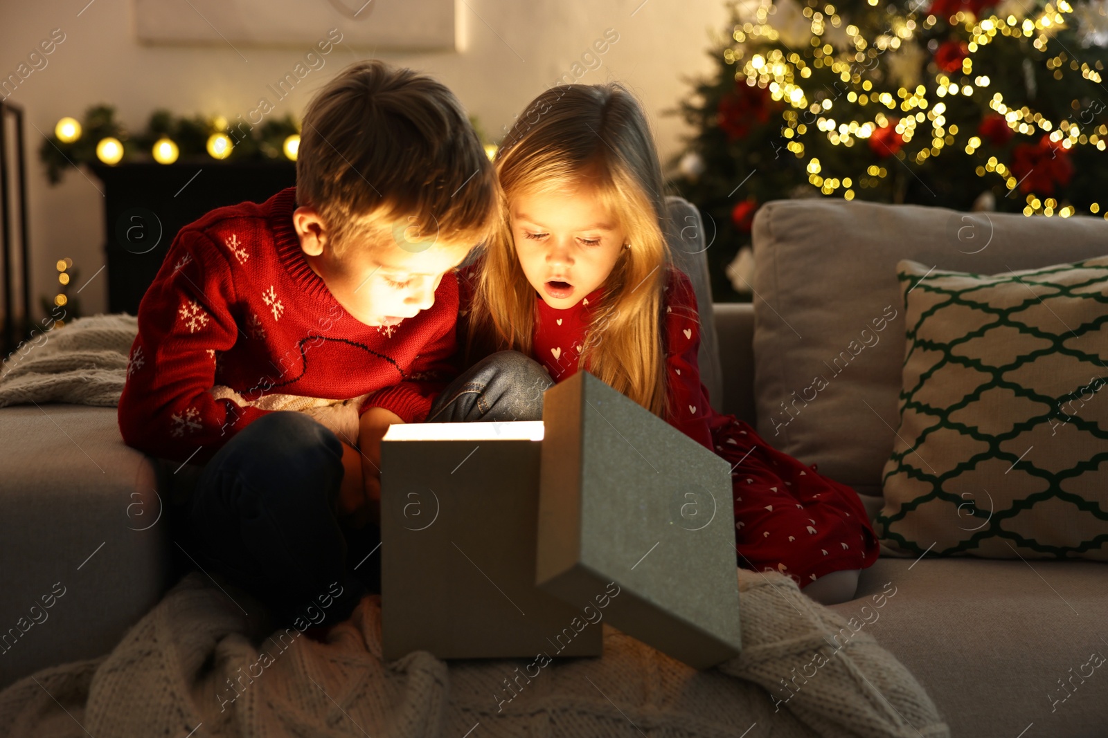 Photo of Surprised little kids near open magic Christmas box at home