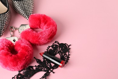 Photo of Fluffy handcuffs, lace mask, high-heeled shoes and lipstick on pink background, flat lay. Space for text