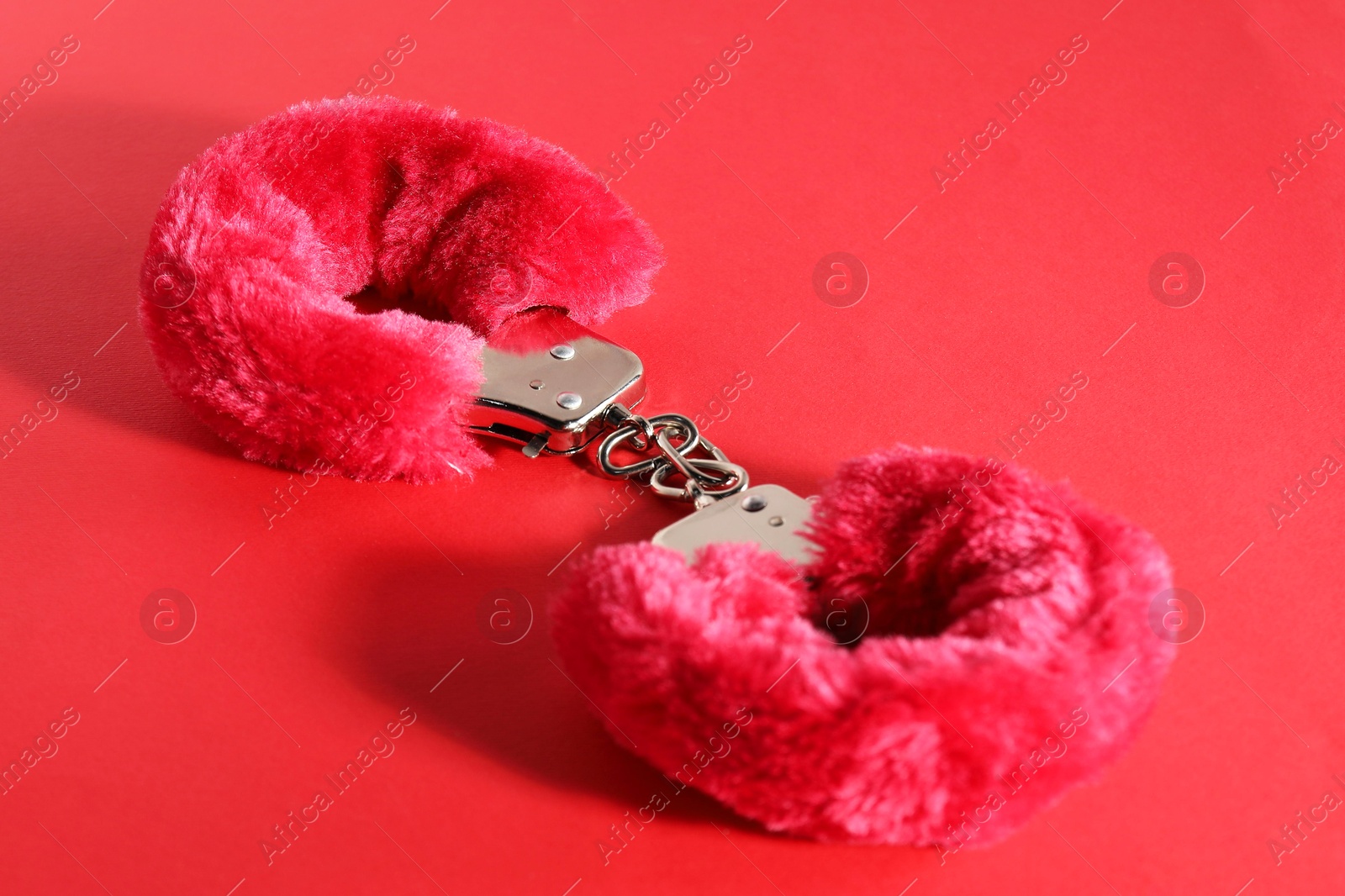 Photo of Pink fluffy handcuffs on color background, closeup. Sex toy