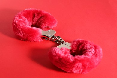 Photo of Pink fluffy handcuffs on color background, closeup. Sex toy