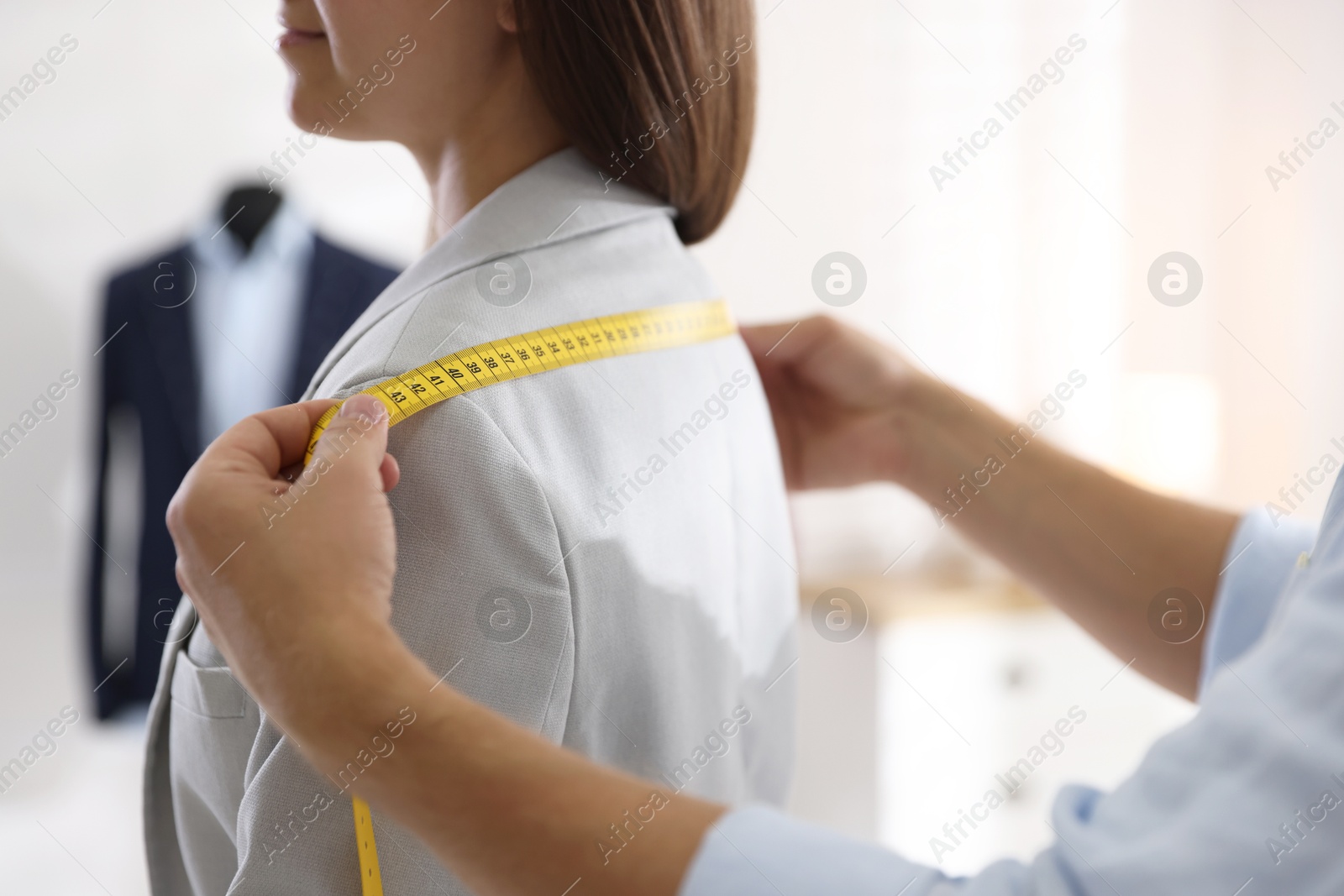 Photo of Man measuring woman's shoulders with tape in atelier, closeup