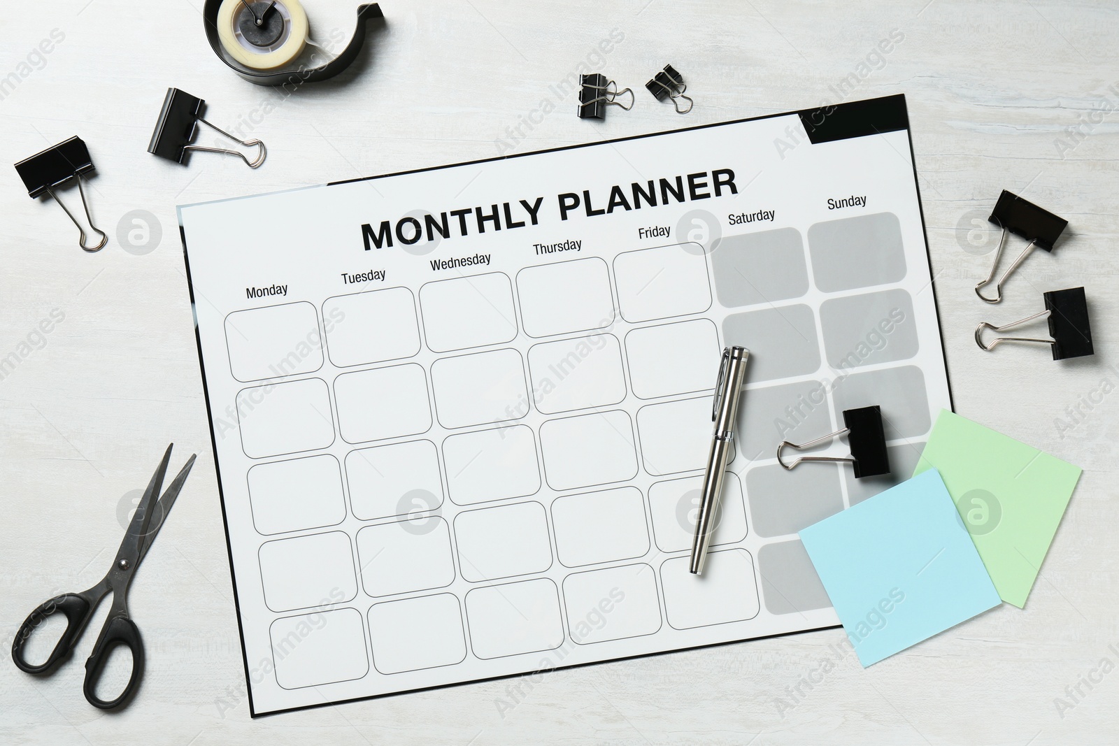 Photo of Timetable. Monthly planner and stationery on white wooden table, flat lay