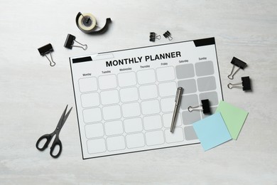 Photo of Timetable. Monthly planner and stationery on white wooden table, flat lay