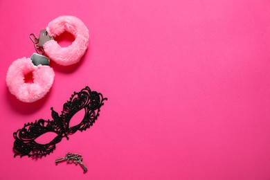 Photo of Fluffy handcuffs, keys and lace mask on pink background, flat lay. Space for text