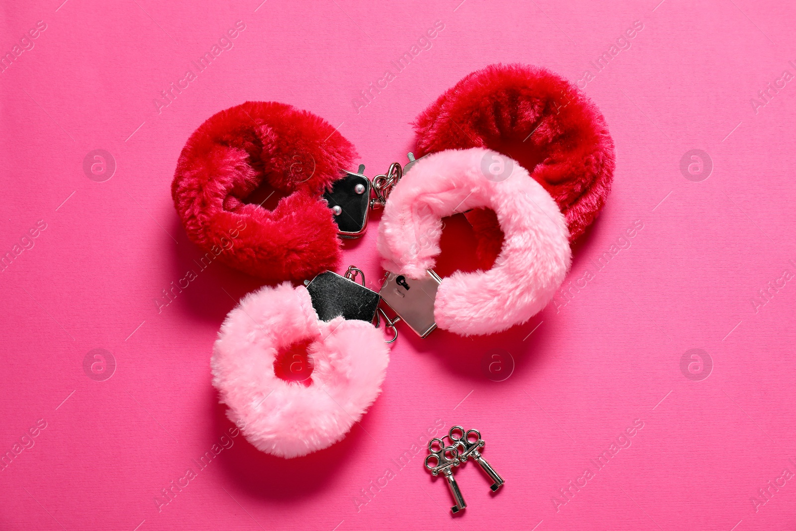 Photo of Fluffy handcuffs and keys on pink background, flat lay