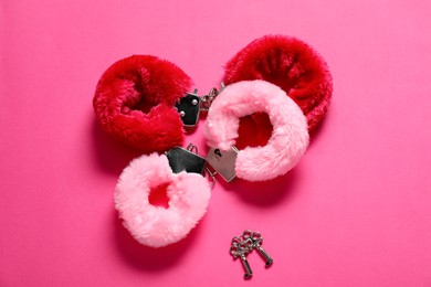 Photo of Fluffy handcuffs and keys on pink background, flat lay