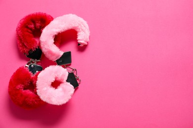 Photo of Fluffy handcuffs on pink background, top view. Space for text