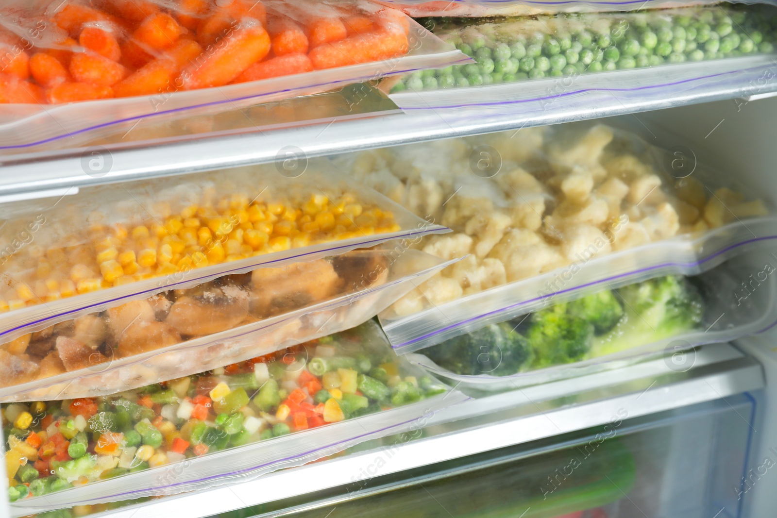 Photo of Plastic bags with different frozen vegetables in refrigerator, closeup