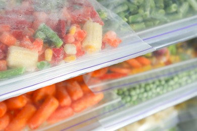 Photo of Plastic bags with different frozen vegetables in refrigerator, closeup