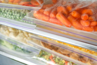 Photo of Plastic bags with different frozen vegetables in refrigerator, closeup