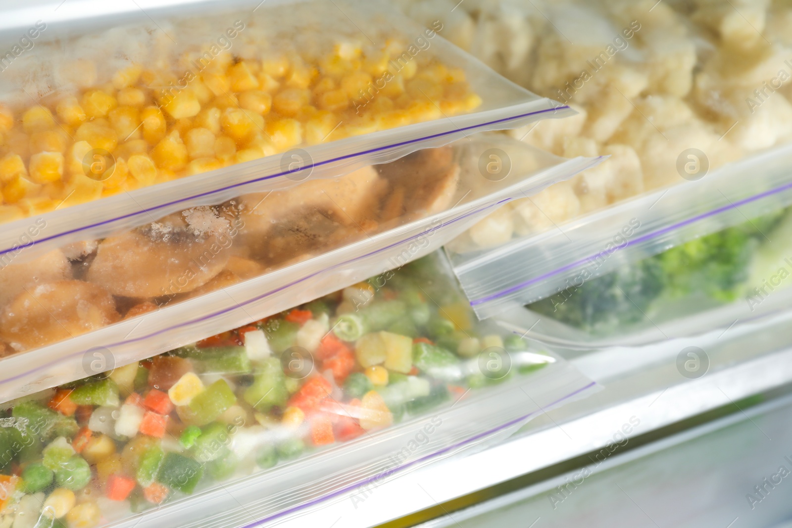 Photo of Plastic bags with different frozen vegetables in refrigerator, closeup