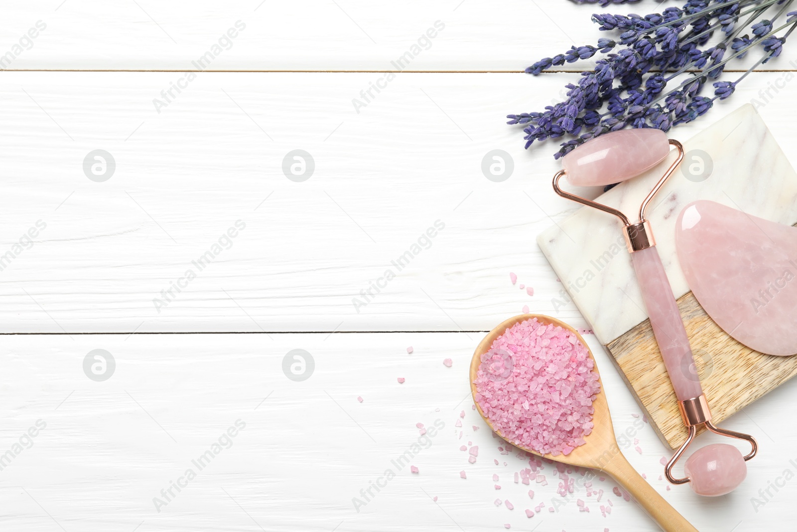 Photo of Face roller, gua sha tool, sea salt and lavender flowers on white wooden background, flat lay. Space for text