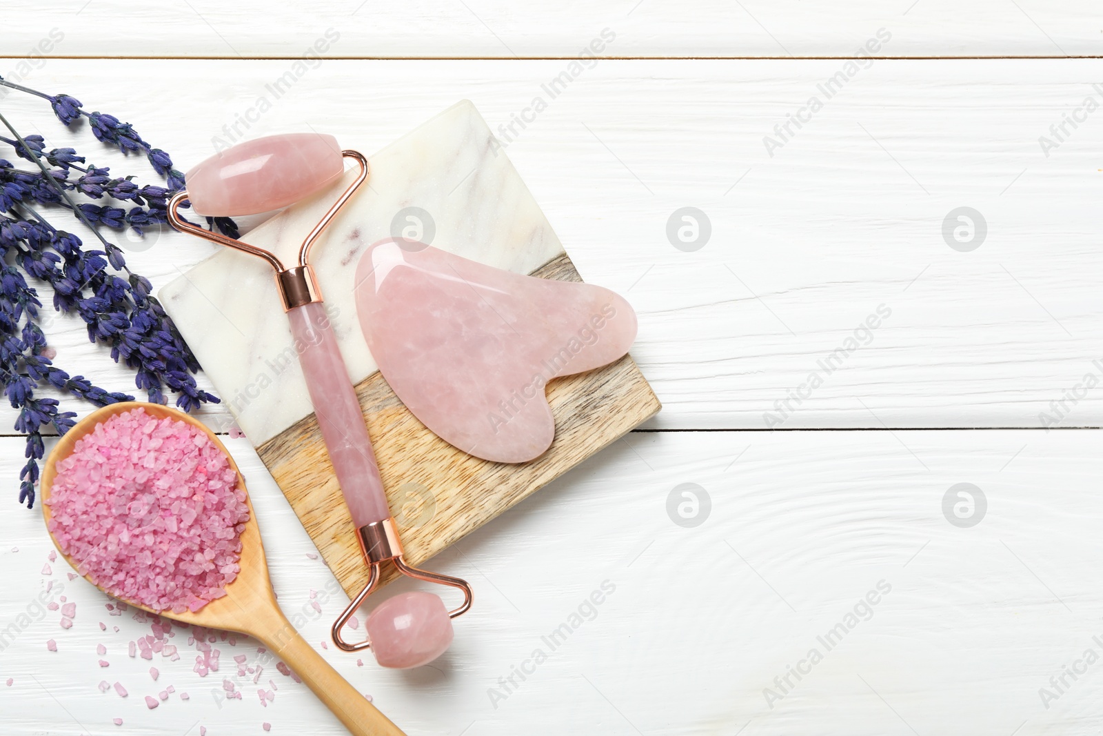 Photo of Face roller, gua sha tool, sea salt and lavender flowers on white wooden background, flat lay. Space for text