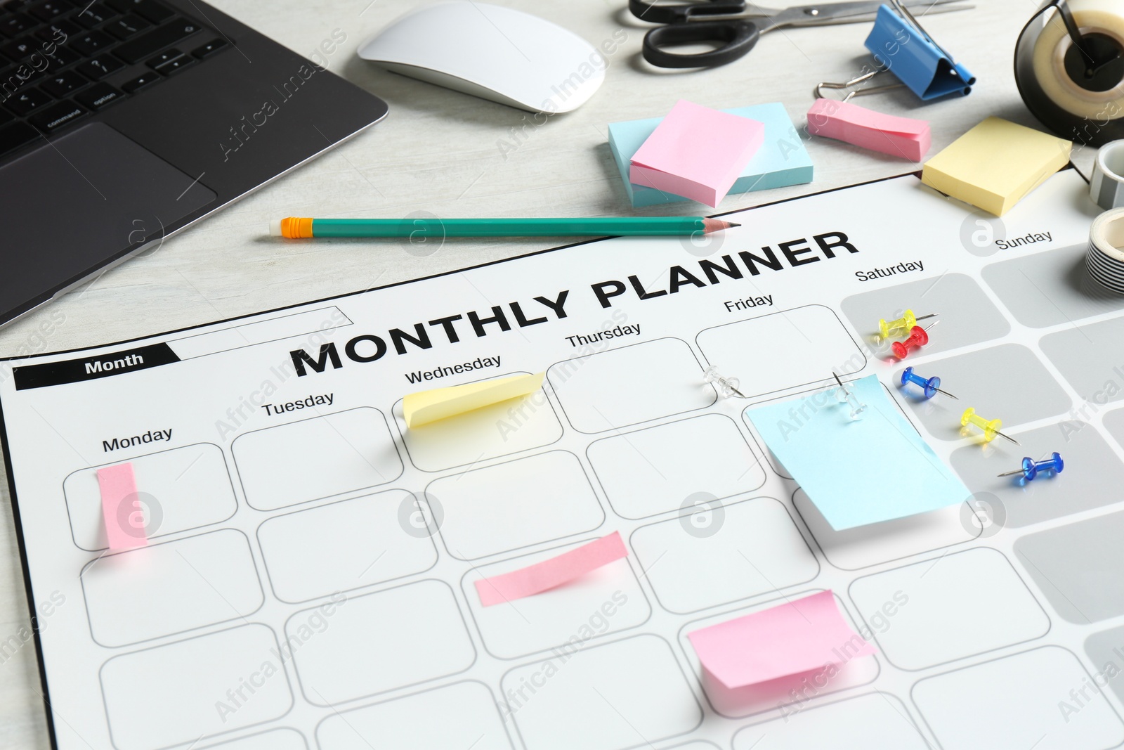 Photo of Timetable. Monthly planner, stationery and laptop on white table, closeup