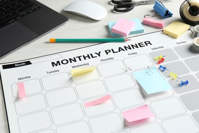 Photo of Timetable. Monthly planner, stationery and laptop on white table, closeup