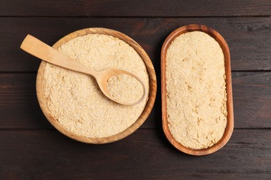 Photo of Oat bran in bowl, spoon and plate on wooden table, top view