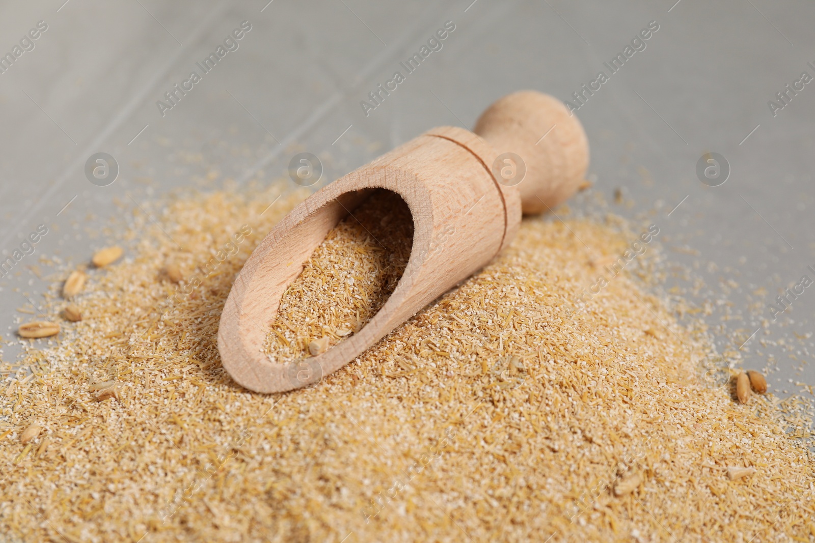 Photo of Oat bran in scoop on grey table, closeup