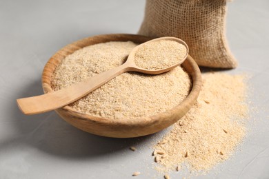 Photo of Oat bran in bowl and wooden spoon on grey table, closeup