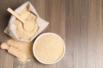 Photo of Oat bran in bowl, scoop, spoon and burlap bag on wooden table, top view. Space for text