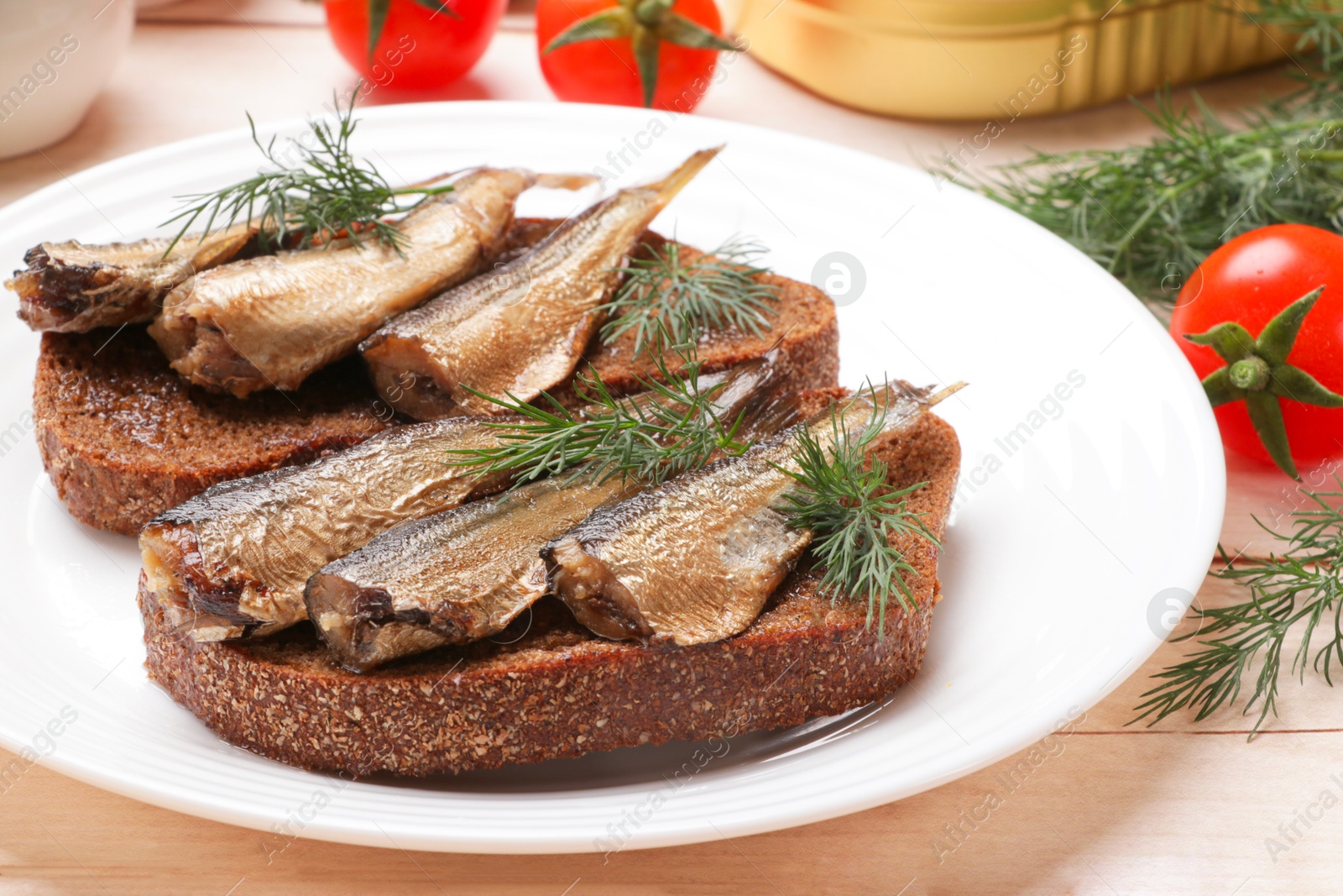 Photo of Delicious sandwiches with sprats, dill and tomatoes on white wooden table, closeup