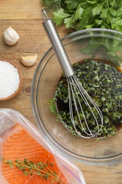 Photo of Soy marinade in bowl, whisk, salmon fillet and spices on wooden table, flat lay