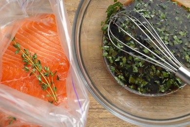 Photo of Soy marinade in bowl and salmon fillet with thyme on wooden table, flat lay