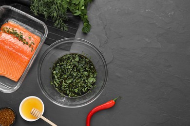 Photo of Soy marinade in bowl, salmon fillet and other products on dark gray textured table, flat lay. Space for text