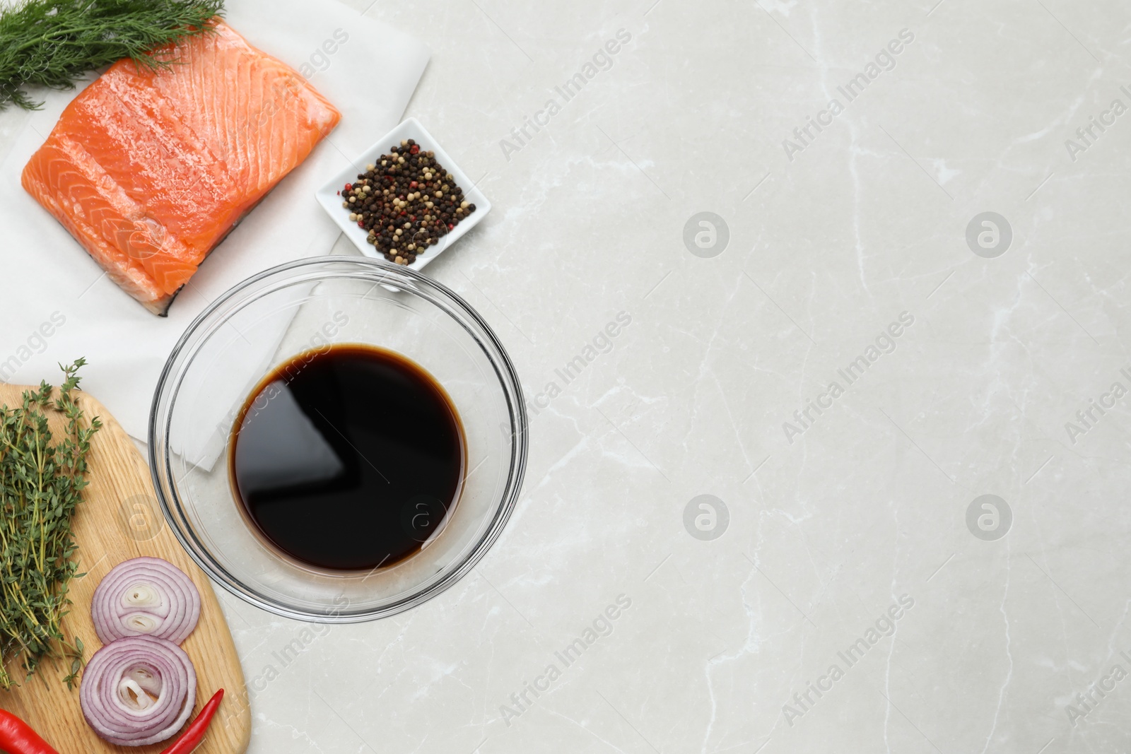 Photo of Soy sauce in bowl, salmon fillet and spices on gray marble table, flat lay. Space for text